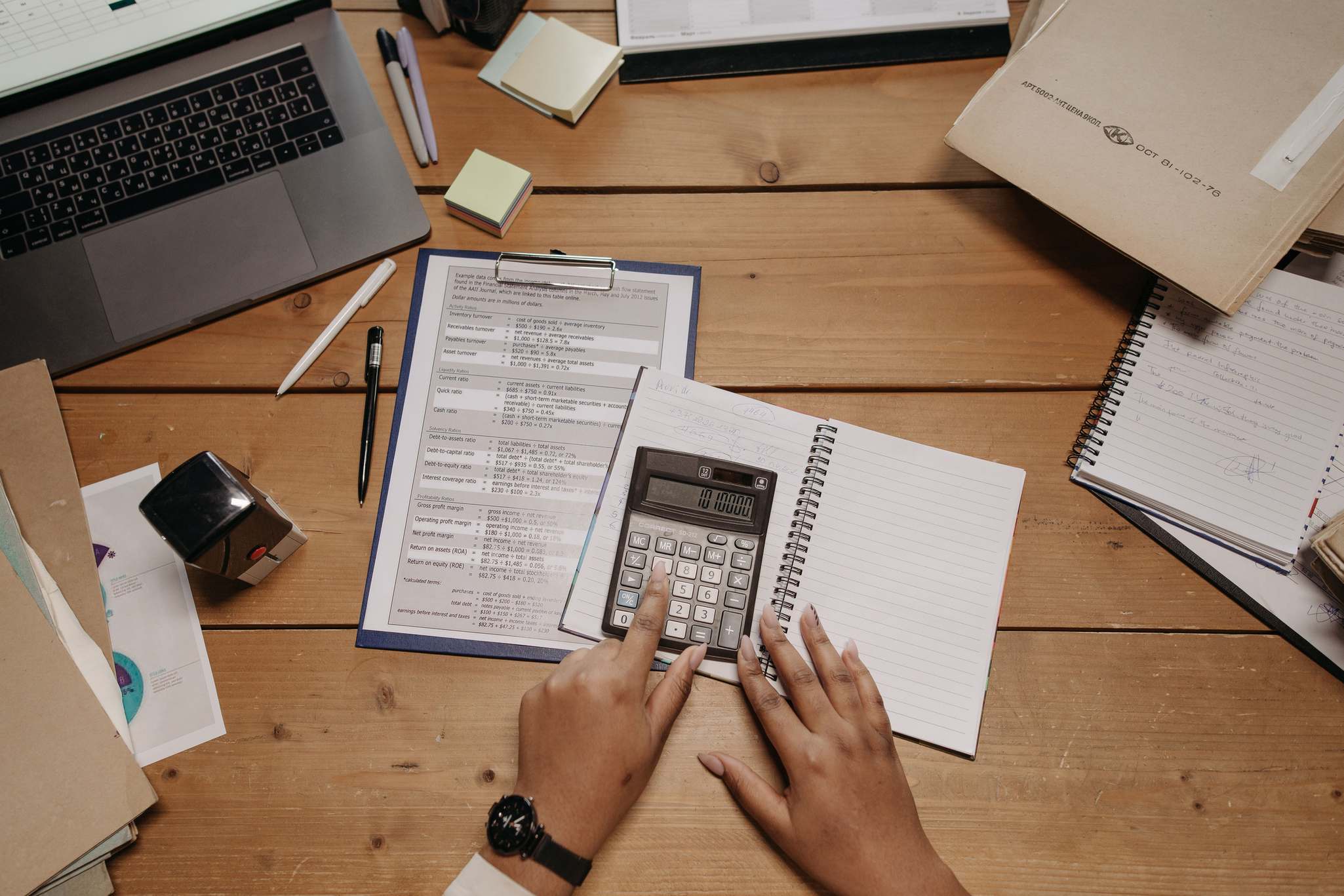 Schreibtisch mit Finanzunterlagen, Taschenrechner und Tabellenkalkulation von oben